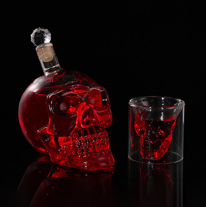 Red skull-shaped bottle and glass with red wine on a black background