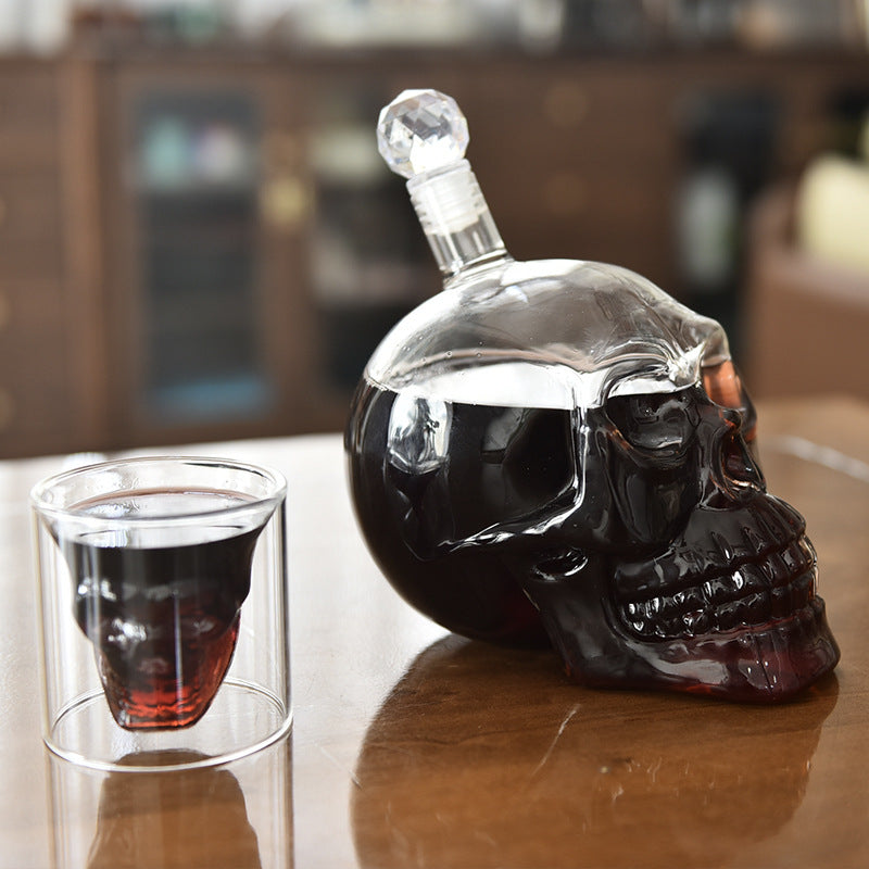 Skull-shaped bottle with a glass of red wine on a wooden surface