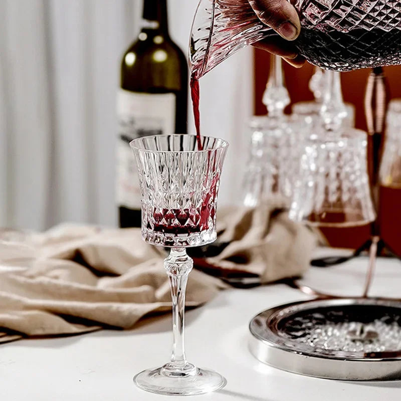 French-style 250ml crystal wine goblet being filled from a matching crystal decanter held by a hand, visible in a softly lit indoor setting.