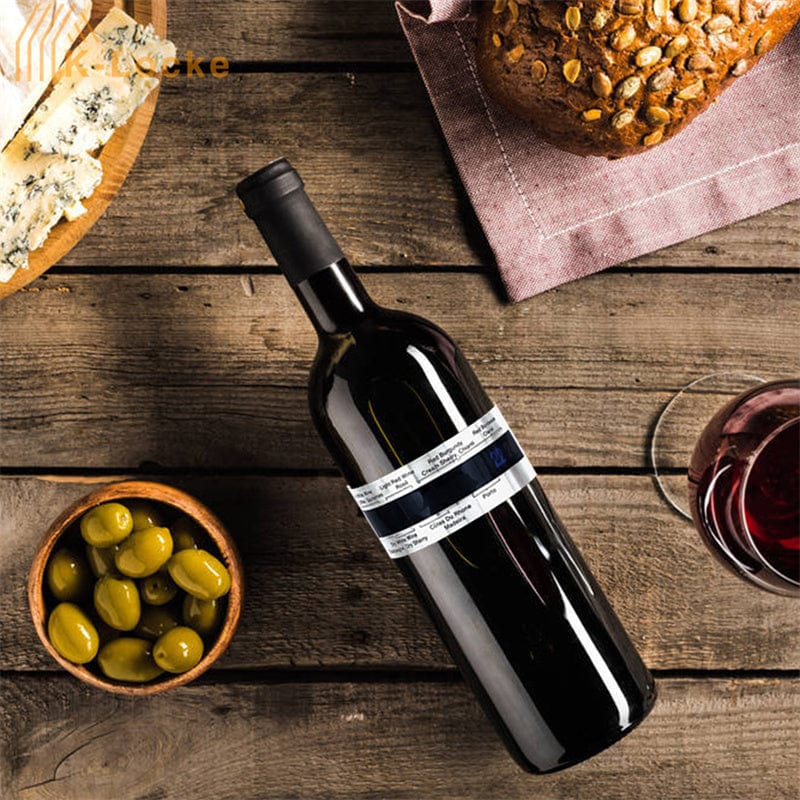 Bottle of red wine on a wooden table with olives, bread, and a glass of wine.