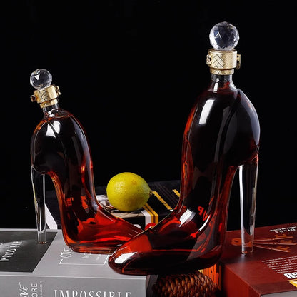 Two high-heeled glass bottles with decorative tops on a dark surface.