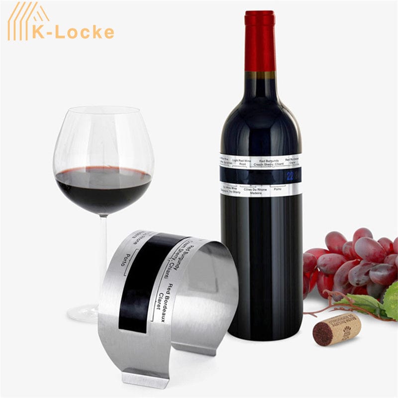 Wine bottle with a label holder, glass of red wine, grapes, and cork on a white background.