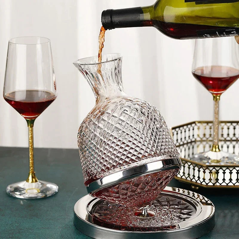  red wine being poured into a Crystal Spinning Decanter with 2 wine glasses with wine on a table.