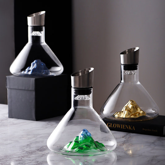 Crystal wine decanter with blue, green, and gold iceberg design displayed on marble table