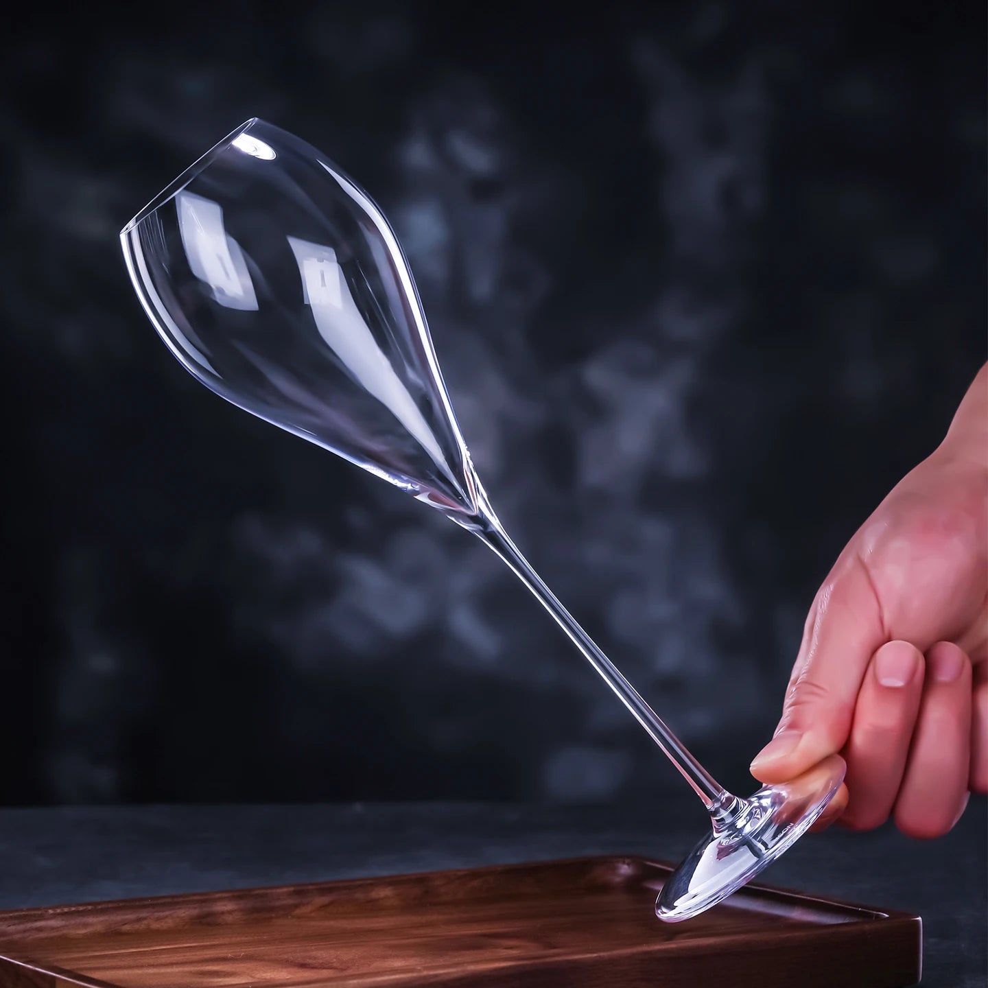 Hand holding a CRISON crystal wine glass against a dark background, showcasing elegant stemware for refined wine tasting and sophisticated entertaining