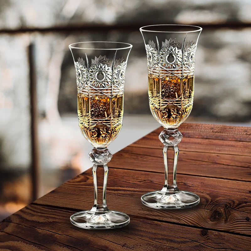 Two ornate crystal champagne flutes filled with sparkling champagne resting on a wooden surface, highlighting elegant glassware design, fine bubbles, and a refined celebration setting.