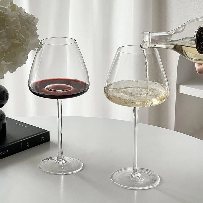 Burgundy crystal wine glasses with red and white wine on a table, showcasing elegant stemware for refined dining and wine tasting