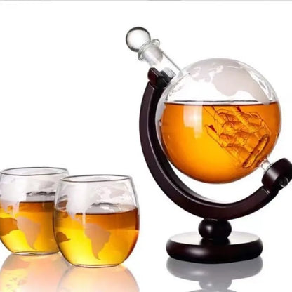 Globe whiskey decanter with ship design filled with amber liquid and two matching glasses