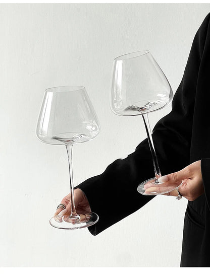 Person holding two sizes of Burgundy crystal wine glasses against a white background, showing size comparison for elegant stemware