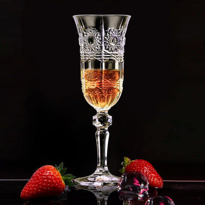 Elegant decorative crystal glass filled with an amber-toned spirit-style pour, paired with fresh strawberries on a dark background, highlighting a luxury serving aesthetic, contrast, and refined glassware presentation.