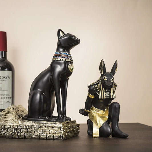 Egyptian Bastet and Anubis resin wine bottle holders displayed on a table with a wine bottle in the background