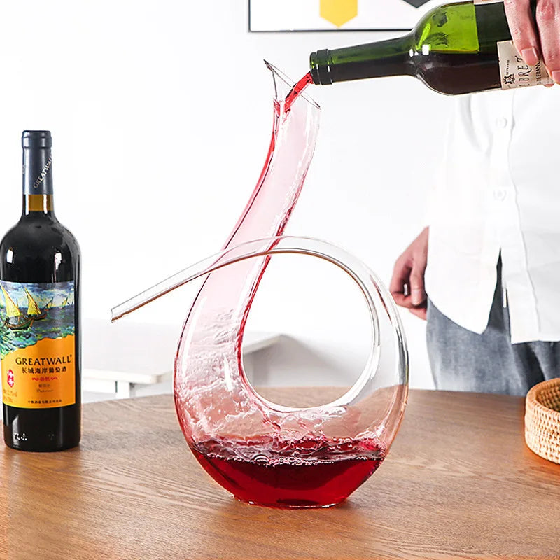 Red wine being poured into crystal wine decanter for aeration and serving on a table
