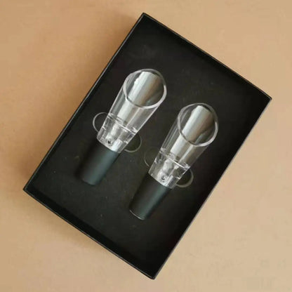 Two wine bottle stoppers in a black box on a beige background