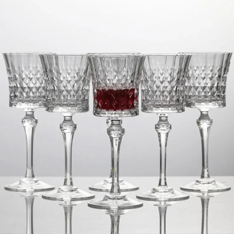Six  French-style 250ml crystal wine goblets with diamond-cut detailing, one filled with red wine