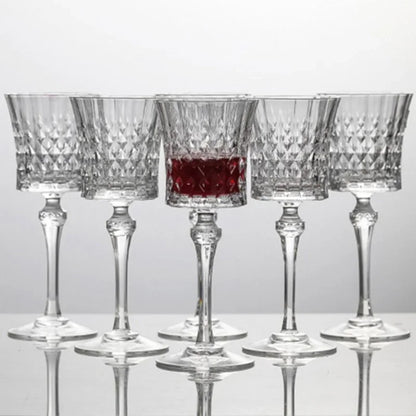 Six  French-style 250ml crystal wine goblets with diamond-cut detailing, one filled with red wine
