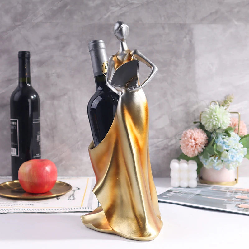Gold lady-shaped wine bottle holder displayed with wine bottles and decorative table accents.