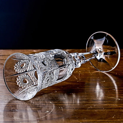 Decorative crystal glass lying on its side on a wooden surface against a dark background, highlighting elegant glassware form, texture, and dramatic luxury styling.