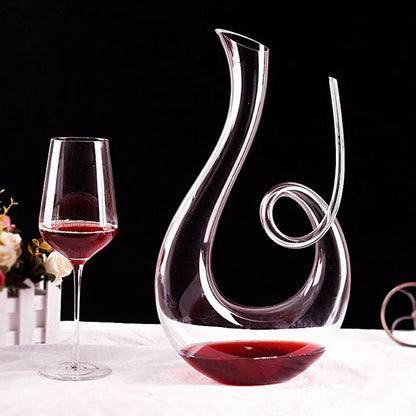 Wide-base crystal wine decanter filled with red wine served beside a glass for aeration and presentation