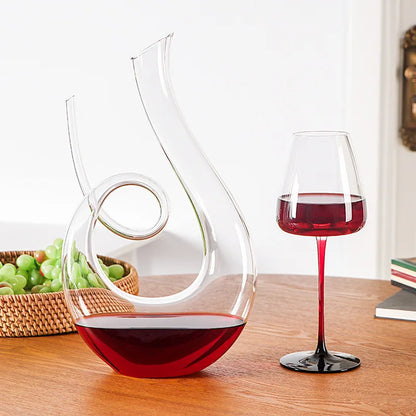 Wide-base crystal wine decanter filled with red wine on wooden table for aeration and serving