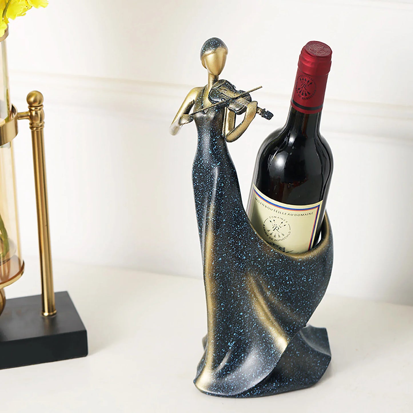 Decorative wine bottle holder featuring a woman playing violin, black and gold glitter finish on white background