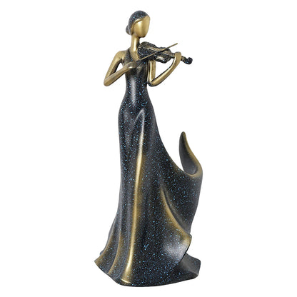 A decorative figurine of a woman in a long flowing gown playing a violin, shown on a plain white background. The figure has a metallic gold finish, while the gown is dark with a blue glittery speckled pattern.
