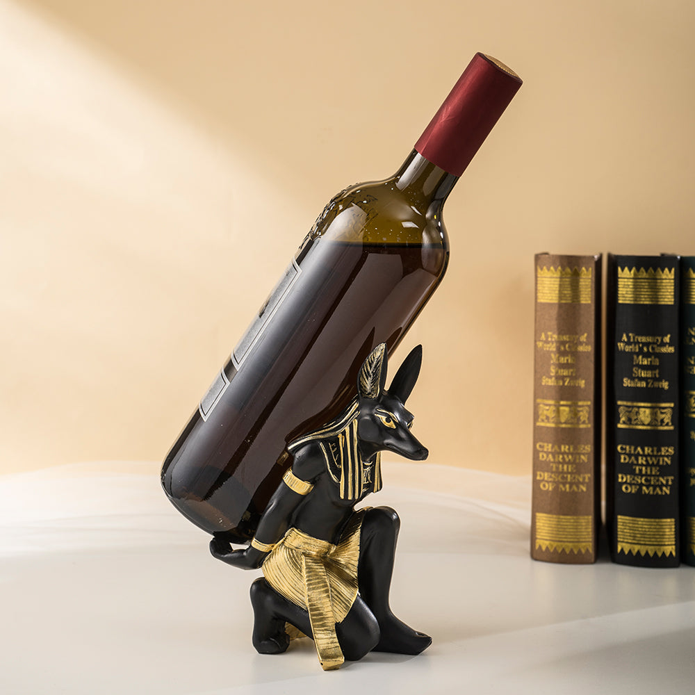 Wine bottle being placed into an Egyptian Anubis resin wine bottle holder